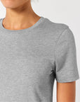 A person wearing a plain gray STTW174 Stella Ella Womens Fitted Loose Knit T-Shirt by Stanley/Stella made from organic cotton against a white background.
