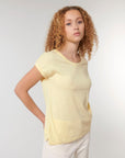 A person with curly hair wearing a STTW112 Stella Rounder Slub Rolled Sleeve T-Shirt by Stanley/Stella and light-colored pants, standing against a plain background.
