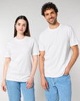 A woman and man stand side by side in plain white BUNDLE X 50 Stanley/Stella Creator 2.0 T-Shirts With Free DTG Print by MyNeedsAreSimple, paired with light blue jeans against a neutral background.