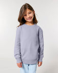 A girl smiling at the camera in her organic cotton Stanley/Stella KIDS' CREW NECK SWEATSHIRT.