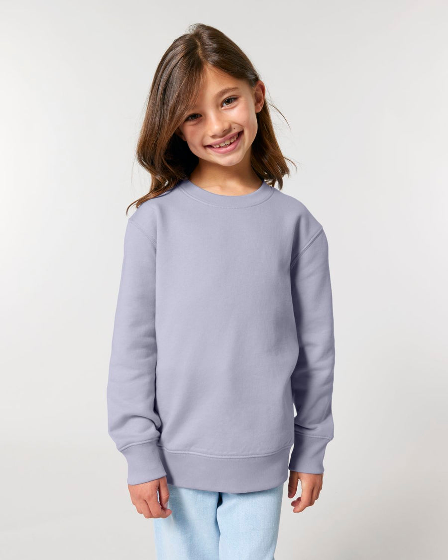 A girl smiling at the camera in her organic cotton Stanley/Stella KIDS' CREW NECK SWEATSHIRT.