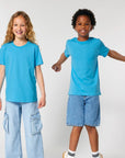 Two children in STTK184 Stella/Stella Mini Creator 2.0 The Iconic Kids’ T-shirts standing next to each other.