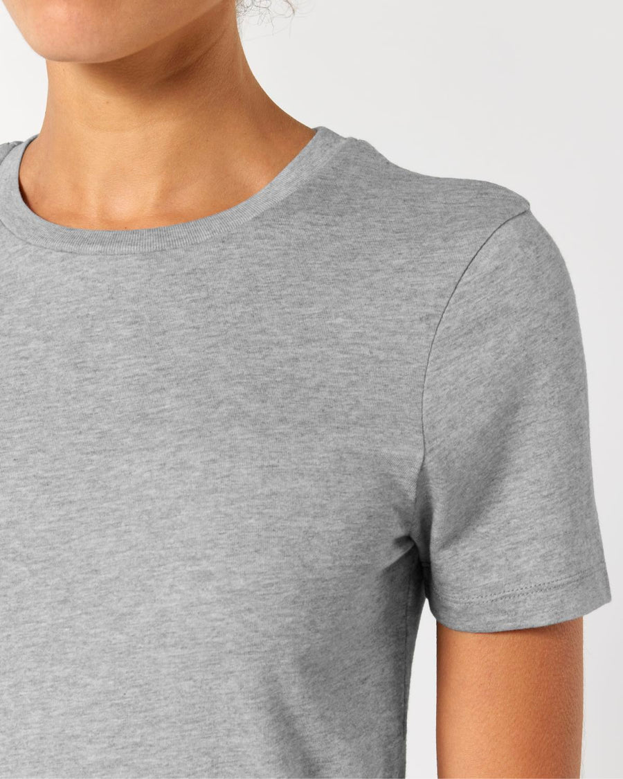 A person wearing a plain gray Stanley/Stella STTW174 Stella Ella Womens Fitted Loose Knit T-Shirt made of soft single jersey against a light background, shown from the shoulders to just above the chest.