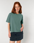 A woman with red hair wearing a green, STTW175 Stella Nova organic cotton t-shirt with a boxy fit and a black denim skirt.