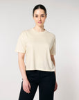 Woman in a STTW175 Stella Nova Womens Boxy T-Shirt by Stanley/Stella made of organic cotton and black pants standing against a neutral background.
