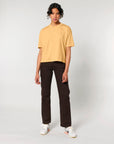 Person standing in a neutral pose wearing a STTW175 Stella Nova Womens Boxy T-Shirt from Stanley/Stella in yellow, dark trousers, and white sneakers.