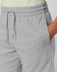 A close-up view of a person wearing light grey STBU186 Stella/Stella Trainer 2.0 The Iconic Mid-light Unisex Jogger Shorts from Stanley/Stella, made from French terry with hands in pockets and a drawstring at the waistband.