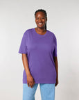 Woman in a purple STTU169 Stanley/Stella Creator 2.0 The Iconic Unisex T-Shirt smiling at the camera.