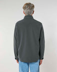 Rear view of a person with short gray hair wearing a MyNeedsAreSimple STJM167 Stanley/Stella Navigator Men's Non-Hooded Softshell jacket and light blue jeans against a plain background.
