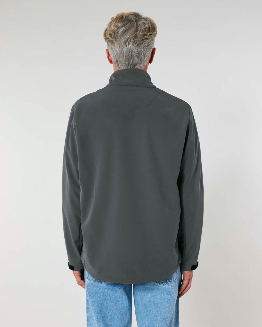 Rear view of a person with short gray hair wearing a MyNeedsAreSimple STJM167 Stanley/Stella Navigator Men's Non-Hooded Softshell jacket and light blue jeans against a plain background.