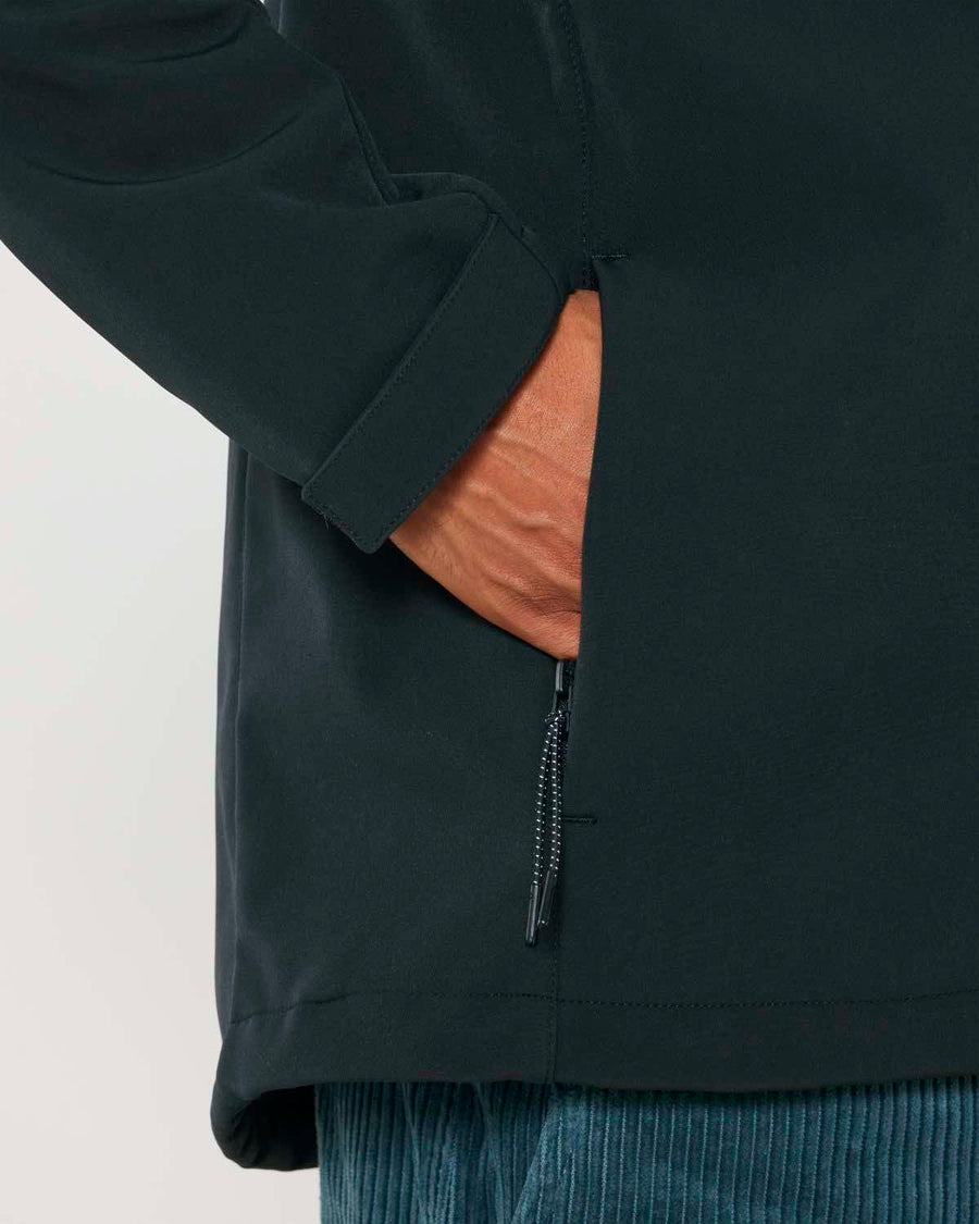 Close-up of a person wearing a MyNeedsAreSimple STJM167 Stanley/Stella Navigator Men's Non-Hooded Softshell jacket with their hand in a side pocket that has a small zipper.