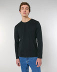A man wearing a Stanley/Stella STTM560 Stanley Shuffler The Iconic Men's Long Sleeve T-Shirt in organic cotton, single jersey and black color.