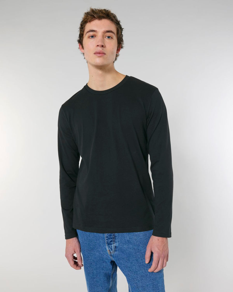 A man wearing a Stanley/Stella STTM560 Stanley Shuffler The Iconic Men's Long Sleeve T-Shirt in organic cotton, single jersey and black color.