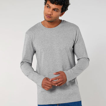 A man wearing a grey Stanley/Stella organic cotton long sleeve STTM560 Stanley Shuffler The Iconic Men's Long Sleeve T-Shirt.