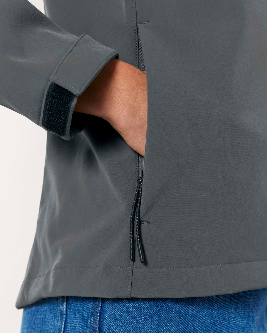Close-up of a person wearing a MyNeedsAreSimple STJW166 Stanley/Stella Navigator Women’s Non-Hooded Softshell jacket with adjustable velcro cuffs and a side zipper, over blue denim jeans.