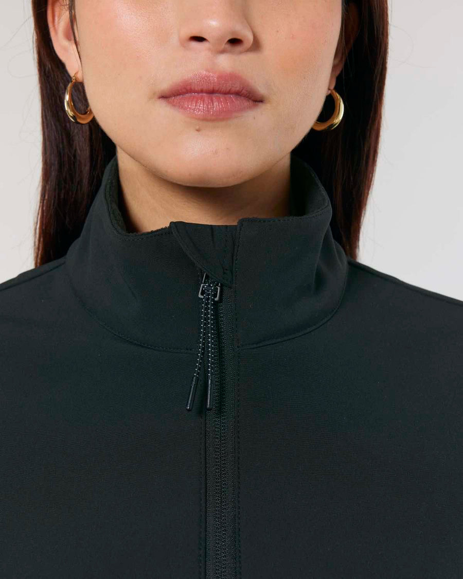 Close-up of a woman wearing a MyNeedsAreSimple STJW166 Stanley/Stella Navigator Women’s Non-Hooded Softshell jacket with a zipper, focusing on her lower face and neckline.