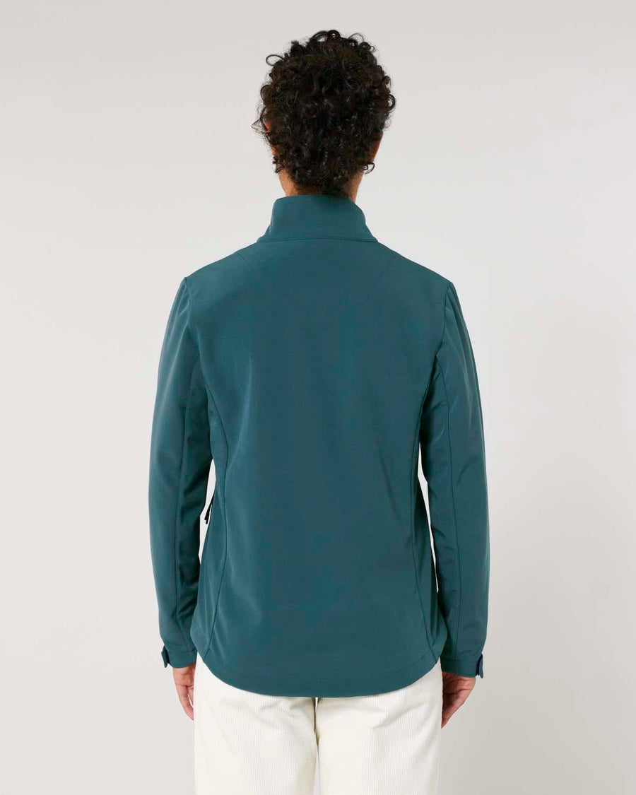 A person viewed from behind wearing a MyNeedsAreSimple STJW166 Stanley/Stella Navigator Women’s Non-Hooded Softshell teal jacket and white pants against a plain background.