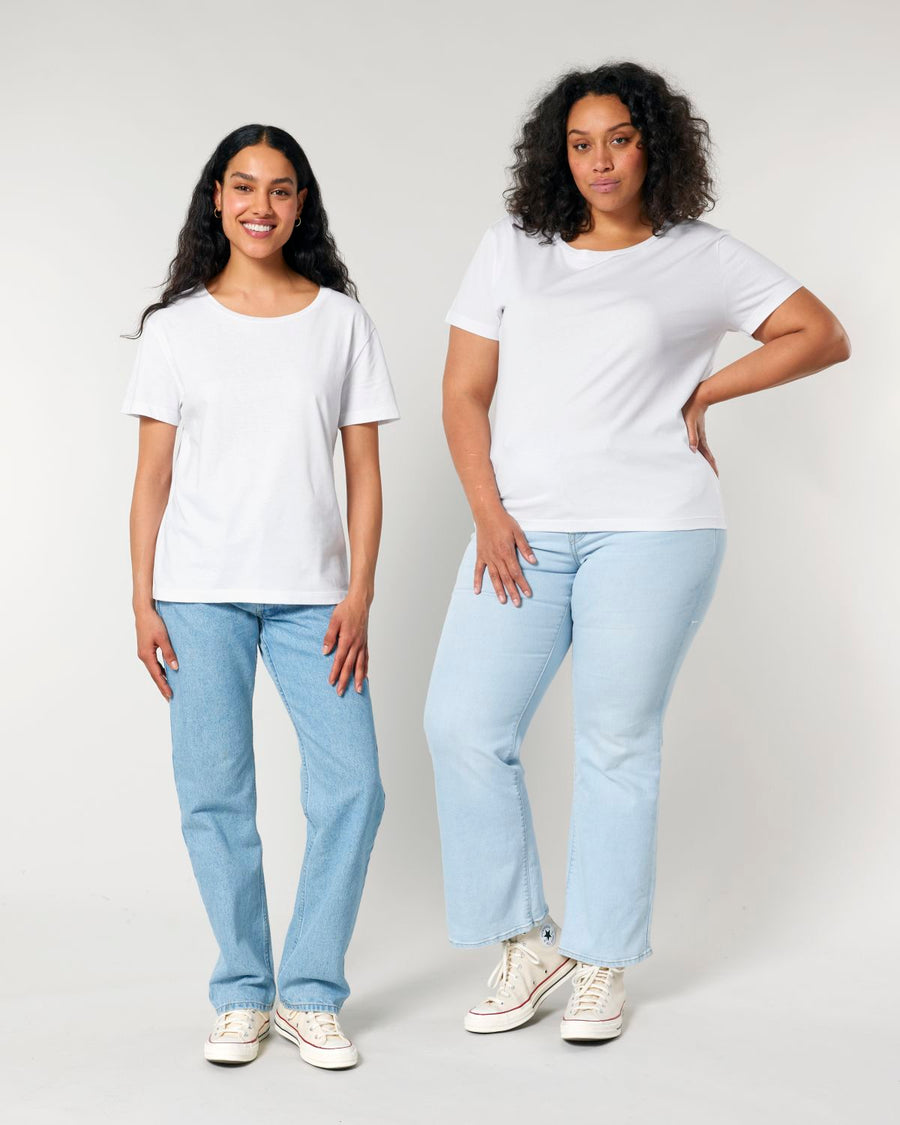 Two women wearing Stanley/Stella STTW173 Stella Serena Mid-Light Scoop Neck T-Shirts and blue jeans standing against a gray background.