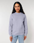 Woman wearing a STSU178 Stella Changer 2.0 The Iconic Unisex Crew Neck Sweatshirt made of organic cotton and blue jeans against a neutral background.
