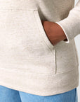 Woman wearing a beige STSU177 Stella/Stella Cruiser 2.0 The Iconic Unisex Hoodie Sweatshirt with her hand in the pocket.