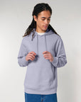 Person in a STSU177 Stella/Stella Cruiser 2.0 The Iconic unisex hoodie sweatshirt with drawstrings, wearing blue denim, standing against a neutral background.