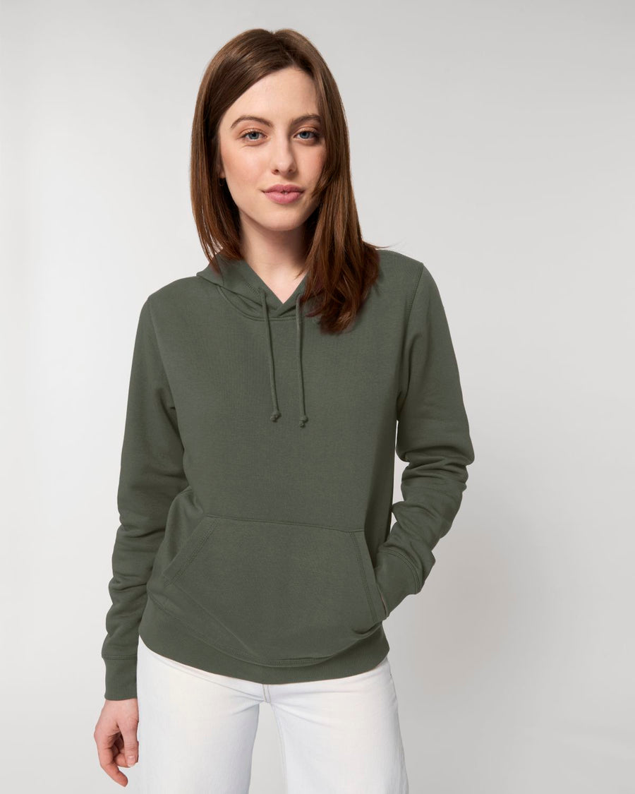 A woman wearing a green STSU812 Stanley/Stella Drummer Hoodie Khaki (C223) sweatshirt.