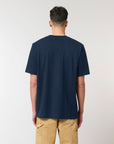 The back view of a man wearing a navy Stanley/Stella Freestyler Heavy Organic Cotton Unisex T-shirt and khaki pants.