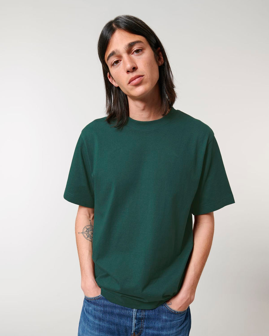 A man wearing a green STTU788 Stanley/Stella Freestyler Heavy Organic Cotton Unisex T-shirt and jeans.