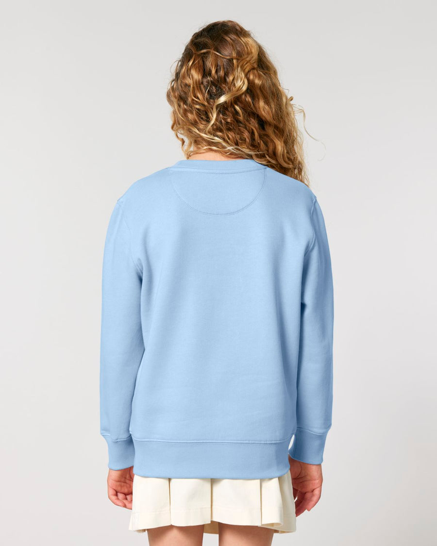 A person seen from behind wearing a Stanley/Stella organic cotton blue sweatshirt and a white skirt.
