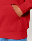A man wearing a red STSK180 Stella kids' hoodie with a pocket.