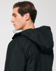 The back view of a unisex man wearing a black hooded Stanley/Stella Padded Parker Jacket with decoration.