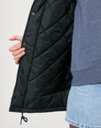 A unisex individual sporting a black quilted jacket with Stanley/Stella padded decoration.