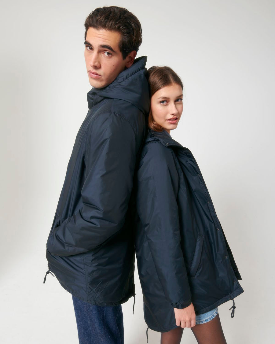A unisex couple wearing matching navy parkas with Stanley/Stella STJU841 Padded Parker Jacket decoration.