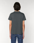 Rear view of a man with shoulder-length dark hair, wearing a Stanley/Stella Rocker Anthracite (C253) organic cotton t-shirt in dark gray and blue jeans, standing against a white background.