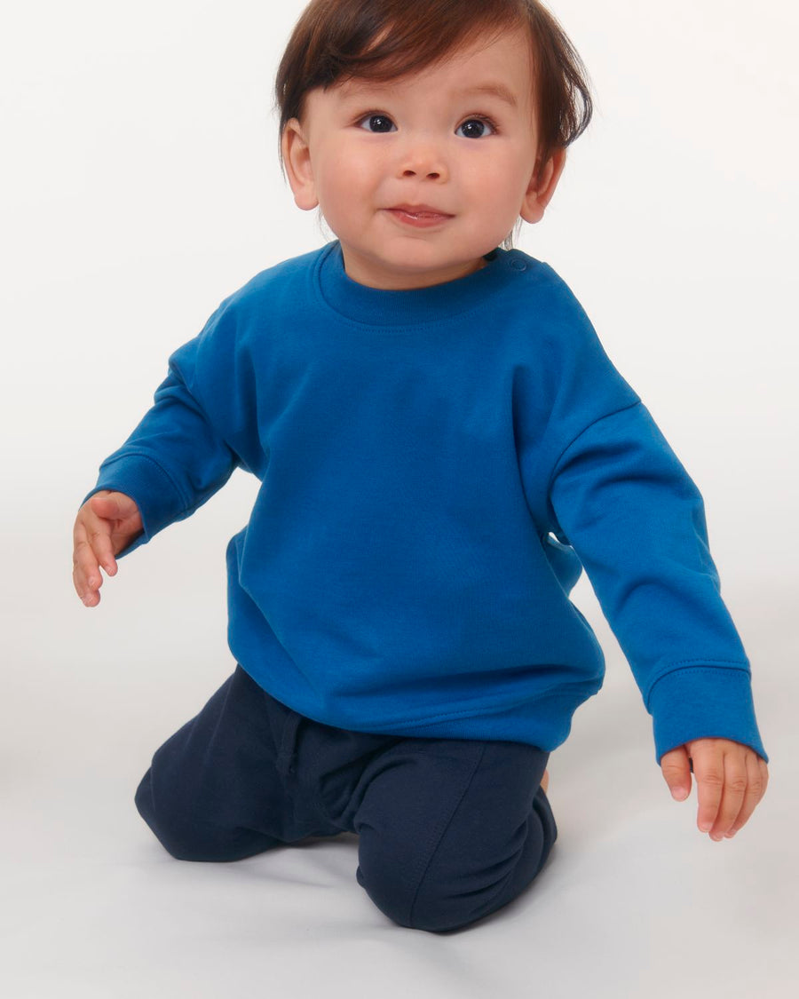A baby in a blue organic ring-spun cotton STSB920 Stella/Stella Baby Changer The Iconic Babies' Crew Neck Sweatshirt.