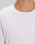 A close up view of a model wearing a Heather Grey Stanley/Stella Shuffler organic cotton long sleeve T-Shirt