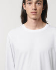 A close up view of a model wearing a white Stanley/Stella Shuffler organic cotton long sleeve T-Shirt