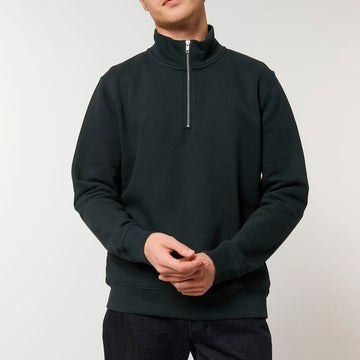 A man wearing a STSM611 Stanley Trucker Men's Quarter Zip Organic Cotton Sweatshirt made of recycled polyester and jeans.