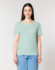 A person with long hair, wearing a Stanley/Stella STTW173 Stella Serena Mid-Light Scoop Neck T-Shirt in light green made from 100% Organic Cotton and blue jeans, stands against a plain background.